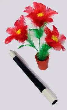 Red feathered flowers in a pot with a black and white handle on a light gray background
