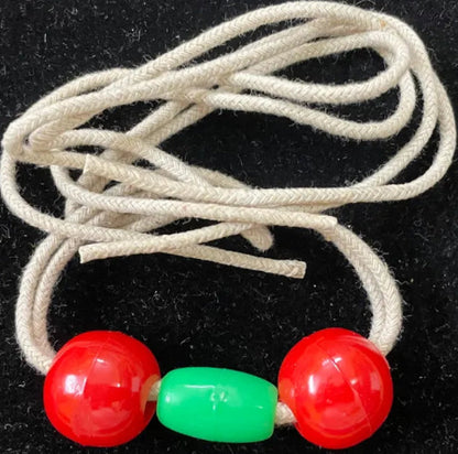 Beige shoelace with red and green beads on a black background