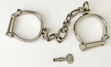 Metal handcuffs with a key on a white background