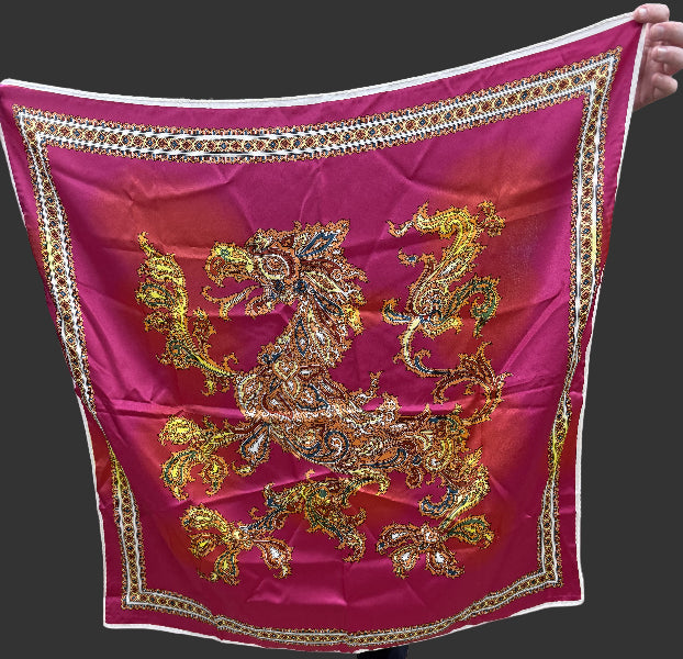 Person holding a pink scarf with gold dragon design in an indoor setting