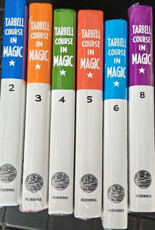 Set of books titled 'Tarbell Course in Magic' with colorful spines on a black surface.