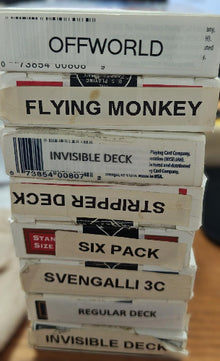 Stack of card game boxes with various names on a blurred background