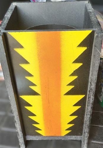 Rectangular metal block with a yellow and orange striped pattern