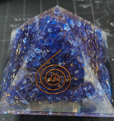 Crystal pyramid with blue crystals and a copper spiral symbol on a dark background