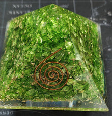 Green crystal pyramid with a copper spiral on a dark background