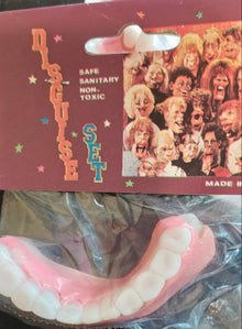 Pink dental model on a dark surface with a colorful card in the background