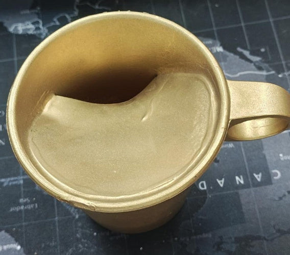 Gold-colored mug on a dark surface with text