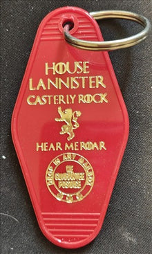 Red keychain with gold text and design on a dark background