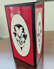 Red book with black and white illustrations on a wooden surface
