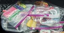 Assorted stationery items including rulers and erasers in clear plastic bags on a black surface.