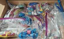 Assorted toys and items in clear plastic bags inside a cardboard box.