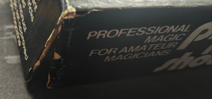 Close-up of a black hat with 'Professional Magic for Amateur Magicians' text on a dark background