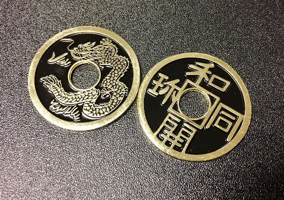 Two metallic coins with dragon design and Chinese characters on a textured surface