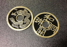 Two metallic coins with dragon design and Chinese characters on a textured surface