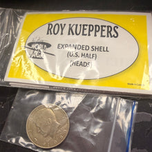 Coin in a clear plastic bag next to a Roy Kueppers packaging on a dark surface