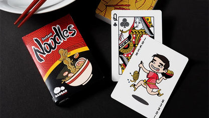Noodle package and playing cards on a black surface