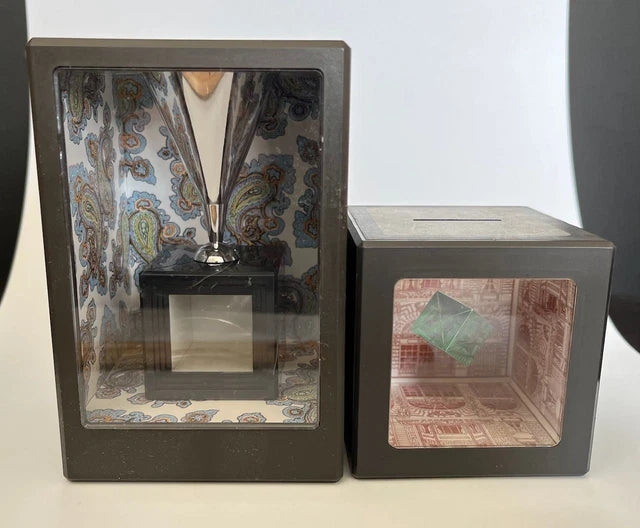 Two decorative boxes with transparent fronts showing interior designs.