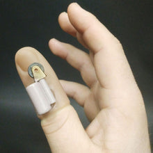 Hand holding a small electronic device on a finger against a dark background