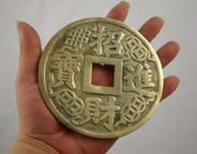Hand holding a gold Chinese coin with text against a white background