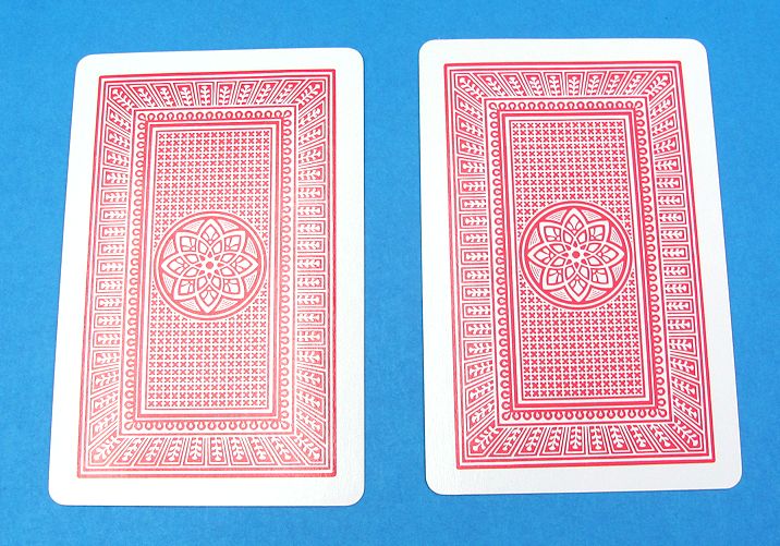 Two red playing cards with a geometric design on a blue background