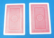 Two red playing cards with a geometric design on a blue background