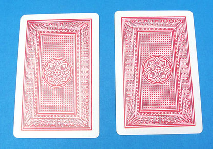 Two red playing cards with a geometric design on a blue background