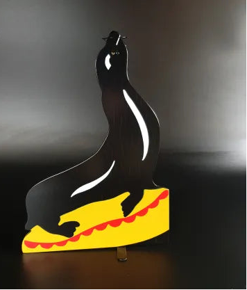 Decorative wall art of a seal on a yellow base with red accents against a dark background