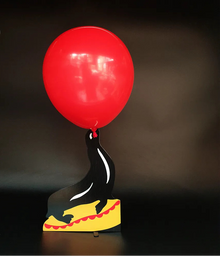 Black seal figurine with a red balloon on a dark background