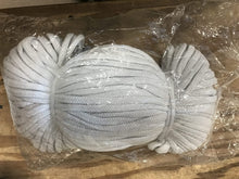 Three balls of white yarn on a wooden surface with plastic wrap.