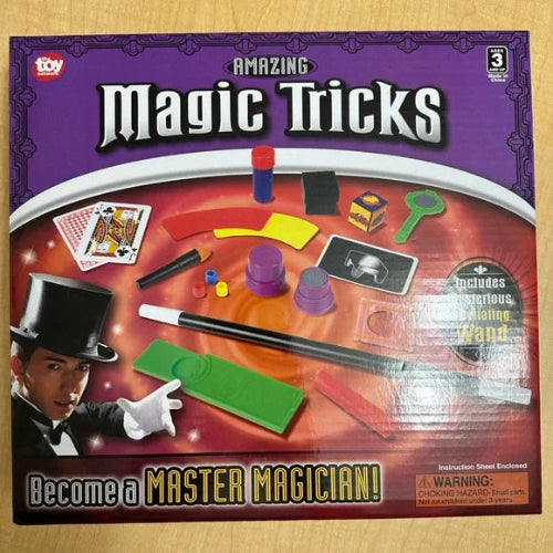 Box of 'Amazing Magic Tricks' set with magician illustration and product images on a wooden surface.