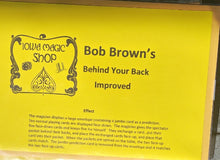 Yellow sign with 'Iowa Magic Shop' and 'Bob Brown's Behind Your Back Improved' text on a yellow background