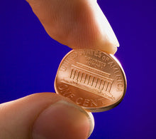 Hand holding a penny against a blue background