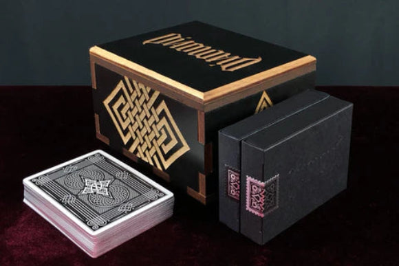 Black and gold playing card box with cards on a dark background