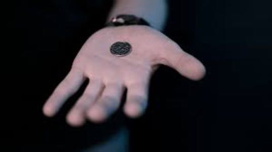 Hand holding a small black object against a dark background