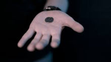Hand holding a small black object against a dark background