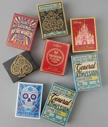 Collection of playing card boxes with various designs on a gray background