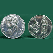Two silver coins with portraits and designs on a green background