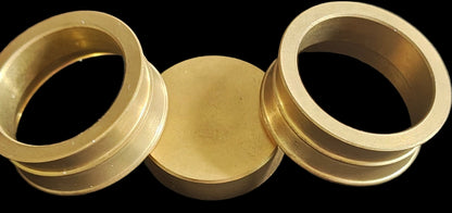 Three Brass objects, all round, the one in the middle is solid.