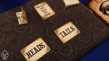 Three playing cards labeled 'Heads', 'Tails', and 'You win this round' on a textured surface.