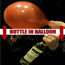 Person inflating a balloon with a bottle inside, against a dark background.