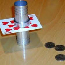 Metallic cone on a playing card with coins on a wooden surface