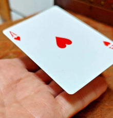 Hand holding a playing card with a red heart symbol