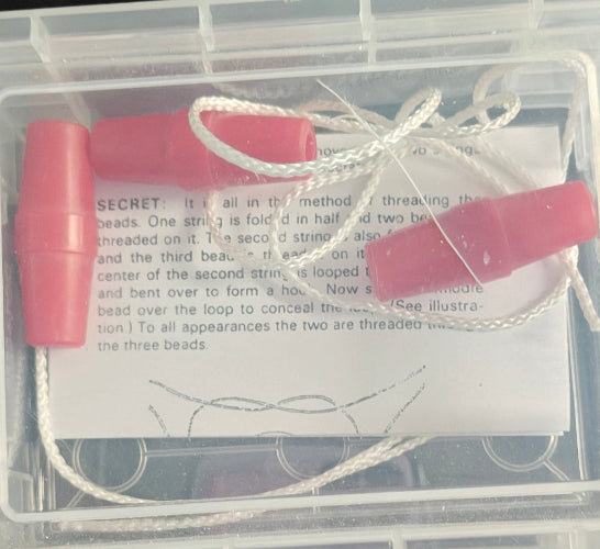 Pink tool with string inside a clear plastic container with text