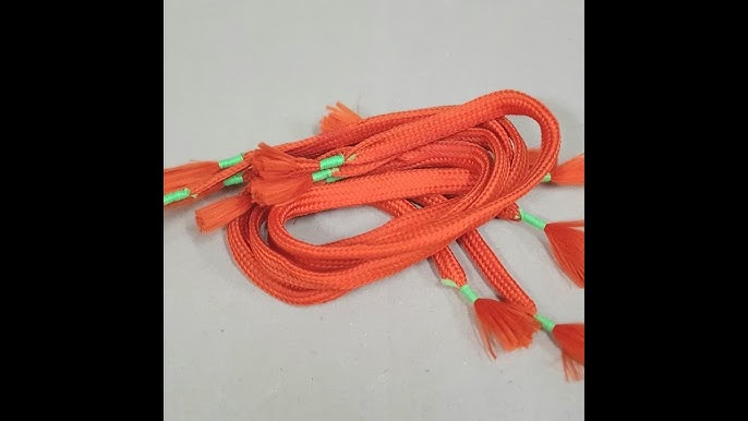 Orange shoelaces with green accents on a light gray background