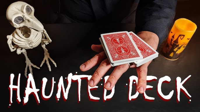 Hand holding red playing cards with a skeleton and candle on a dark background, featuring 'Haunted Deck' text.