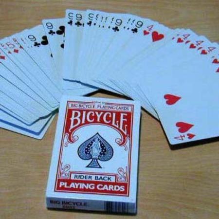 Bicycle playing cards with a deck of cards fanned out on a wooden surface.