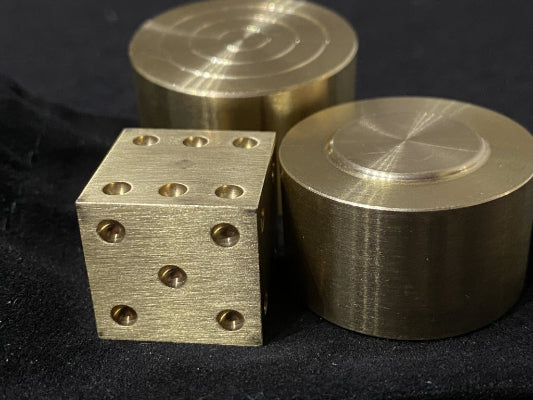 Bronze dice and cylindrical objects on a black background