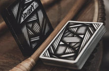 Two playing card decks with geometric patterns on a wooden surface