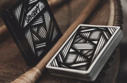 Two playing card decks with geometric patterns on a wooden surface