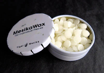White wax pieces in a container with 'MesikaWax' branding on a dark background